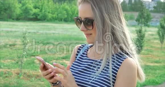 幸福的年轻女人带着眼镜在手机上输入短信视频的预览图