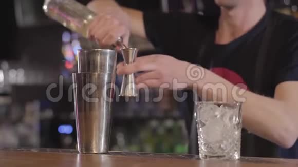 英俊的调酒师用摇床在漂亮的现代酒吧里用不同的饮料做酒精鸡尾酒视频的预览图