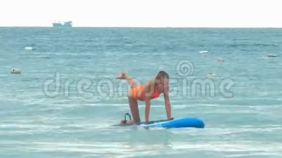 女孩摆姿势平衡猫桨板与海洋视频的预览图