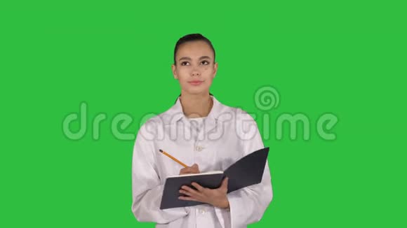 有创意的年轻女医生拿着笔记本走在绿色屏幕上Chroma键视频的预览图