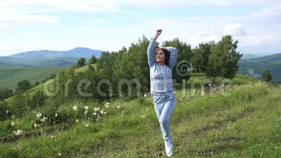 美丽的女孩在田野上奔跑和旋转背景是山脉自由概念户外快乐的年轻女人慢慢慢慢视频的预览图