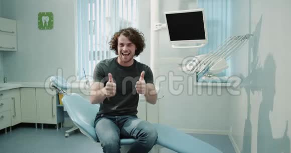 一位年轻的病人坐在牙医椅上等待口腔检查心情愉快面带微笑视频的预览图