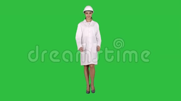 成熟的女工程师戴着安全帽在绿色屏幕上行走时用手向产品或文字表示视频的预览图