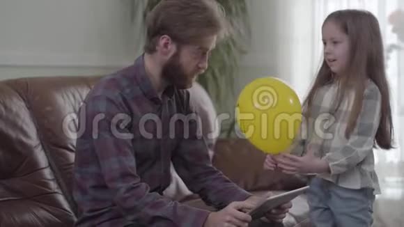 一幅集中留胡子的人用平板电脑特写的画像小女孩试图给男人一个视频的预览图