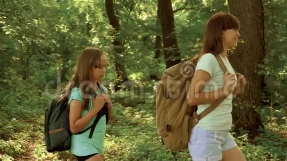 带背包的快乐女孩旅行者穿过森林的灌木丛儿童游客在夏季公园旅行视频的预览图