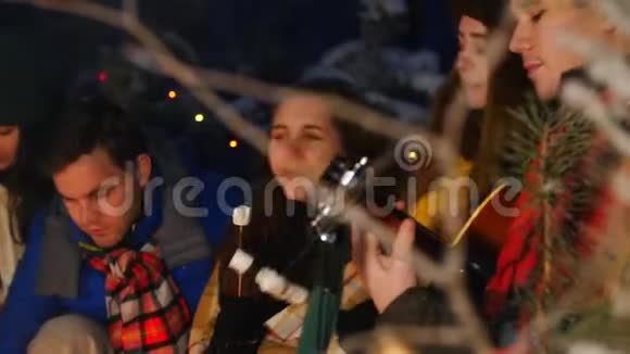 一群朋友在冬林玩得很开心坐在篝火旁一个弹吉他的年轻人视频的预览图