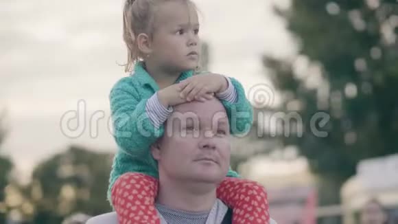 年轻的父亲骑着小女儿在夏天的公园散步视频的预览图