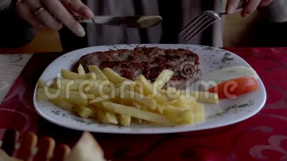在餐馆里女人的手在盘子上切肉视频的预览图