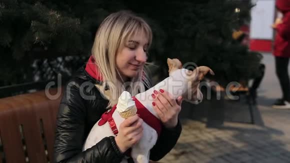 慢动作快乐的女孩与冰淇淋坐在她的狗在长凳上和摆姿势女人爱抚一只狗视频的预览图