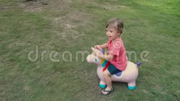 可爱的金发小男孩骑着马玩具独角兽视频的预览图