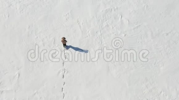 孤独的人在白雪皑皑的北极沙漠中行走从上面看孤独和克服视频的预览图