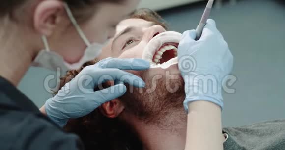 一个年轻男子在一张牙列椅子上戴着护口器和完美的白色牙齿的肖像有口腔卫生的程序视频的预览图