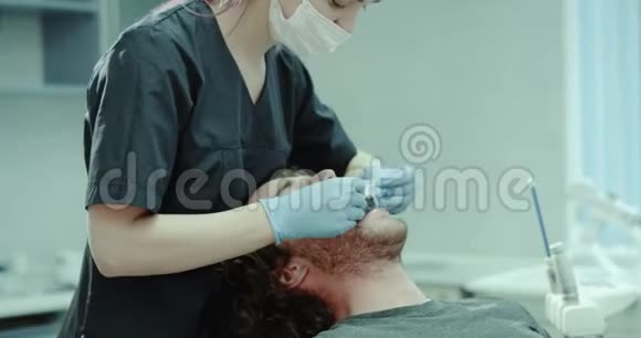 牙科诊所的年轻病人坐在牙列椅上牙医把护口放在嘴上4k视频的预览图