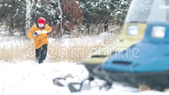 那孩子穿过雪堆朝森林里一辆雪车的方向跑视频的预览图