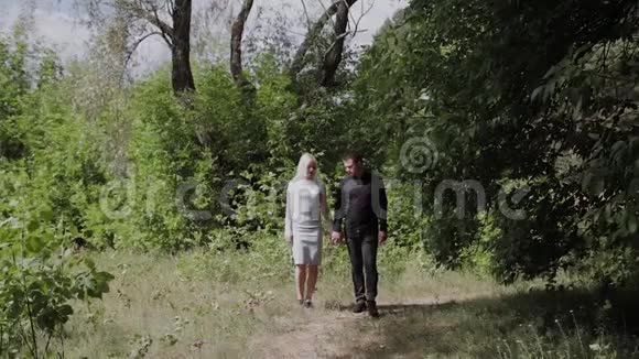 幸福的年轻夫妇相爱手牵手走在阳光明媚的森林里视频的预览图