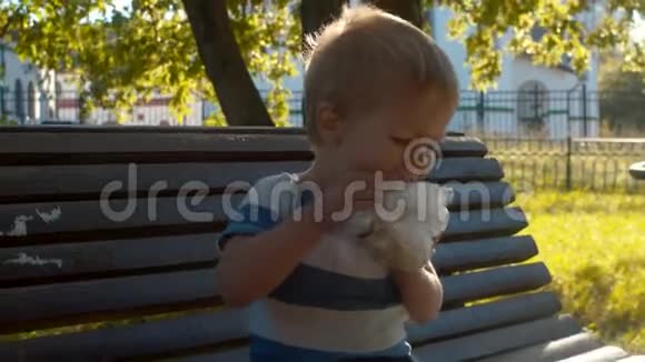 坐在长凳上吃面包的小孩视频的预览图