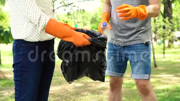 一群带手套的志愿者把垃圾收集到公园的垃圾袋里视频的预览图