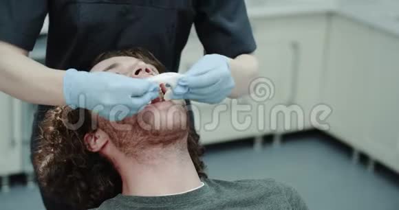 一位女牙医的牙科诊所里的一位年轻病人一位坐在蓝色牙科椅上的病人的口腔保护装置视频的预览图