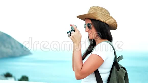侧视女性专业摄影师使用老式摄像机拍摄海滨照片视频的预览图