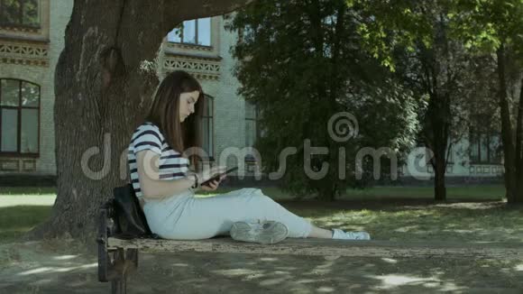 可爱的女孩与平板电脑在长凳上联网视频的预览图