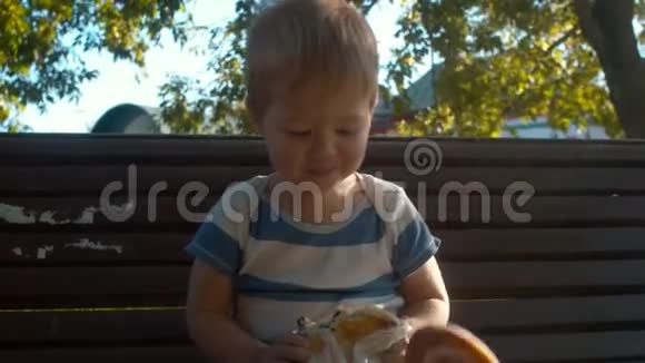 小男孩坐在长凳上吃面包视频的预览图