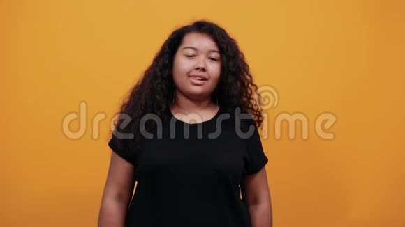 疯狂的美国黑人年轻女士体重超重在隔离的橙色墙上视频的预览图