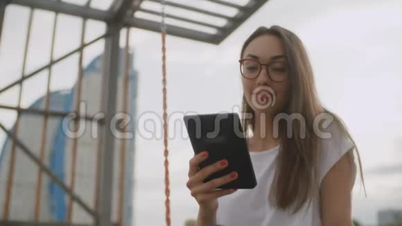 戴眼镜的美女在公园看电子书视频的预览图