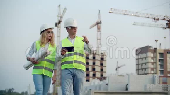两名工业工程师戴着安全帽手持平板电脑工作和与图纸交谈检查视频的预览图