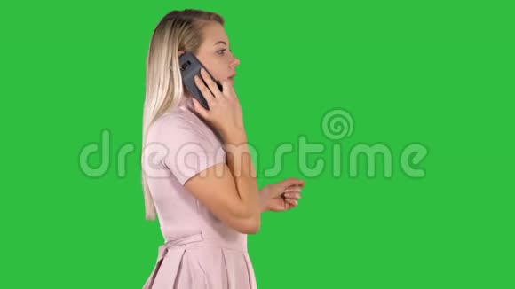 可爱的女人在绿色屏幕上走来走去在电话里聊天Chroma键视频的预览图