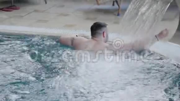 快乐的人在瀑布下游泳在游泳池里摆姿势视频的预览图