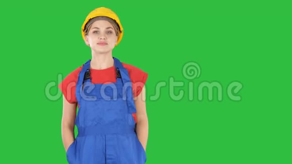 微笑的建筑工人妇女站着变换姿势折叠双手双手放在臀部双手放在绿色的口袋里视频的预览图