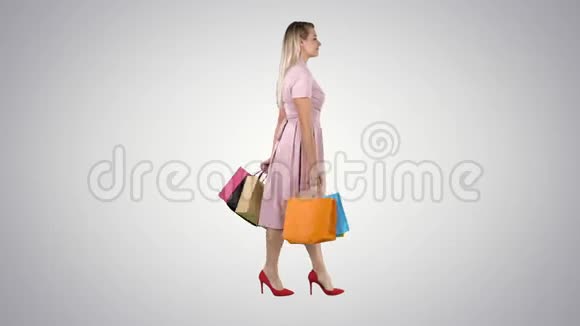 年轻的女人带着购物袋看着梯度背景上的橱窗展示视频的预览图