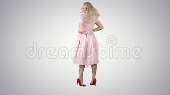 穿着粉红色连衣裙的女人转过身来像在渐变背景上的镜子里一样看着她自己视频的预览图
