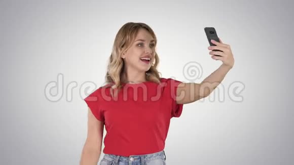 开朗的女性博主在渐变背景下行走时录制视频到现代电话的前摄像头视频的预览图