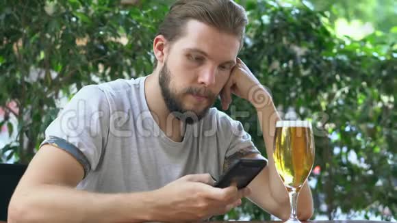 年轻人在看智能手机喝啤酒视频的预览图