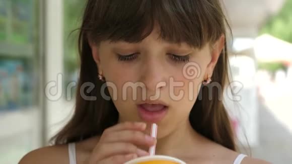 美丽的女孩喝着稻草鸡尾酒微笑着在城市里散步特写镜头少女喝清凉饮料视频的预览图
