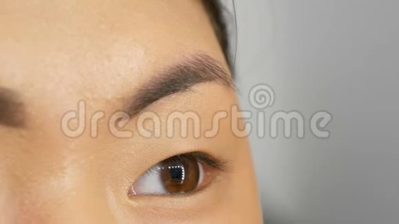 专业化妆师用特殊的画笔在一个亚洲韩国女性模特的脸上画眉毛视频的预览图