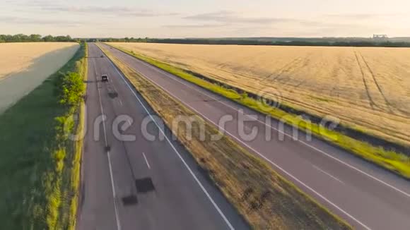 日落时分汽车沿着麦田之间五颜六色的公路行驶汽车沿着两条路行驶视频的预览图
