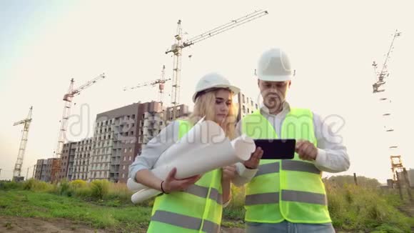 两名工业工程师戴着安全帽手持平板电脑工作和与图纸交谈检查视频的预览图