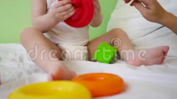 孩子和妈妈在床上玩多种颜色的立方体和戒指学前和幼儿园儿童的教育玩具视频的预览图