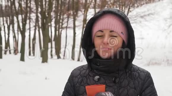 在冬季森林里喝热咖啡的亲密美丽的女人视频的预览图