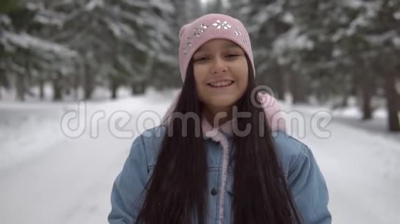 女孩在冬天的森林里站着用手套打雪视频的预览图