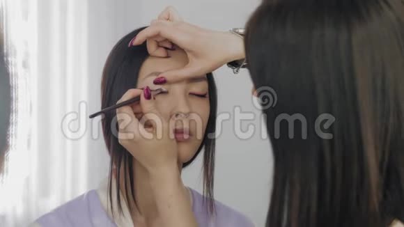 年轻的亚洲模特化妆过程中的脸视频的预览图