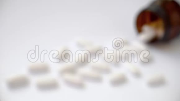 许多白色的大椭圆形药片躺在棕色玻璃瓶附近视频的预览图