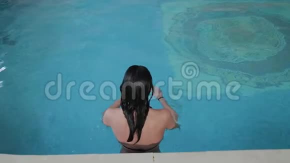 美丽的女孩游到游泳池的边缘视频的预览图