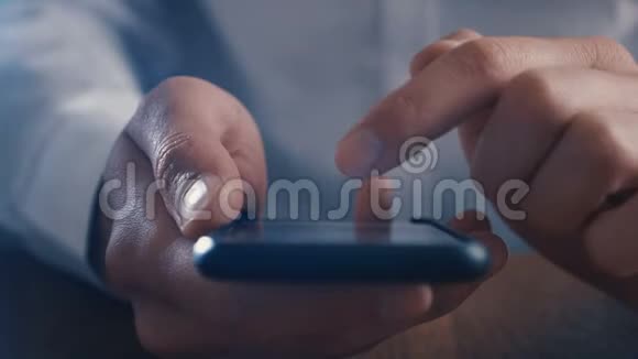 特写商人在黑暗中用手指在智能手机上滚动视频的预览图