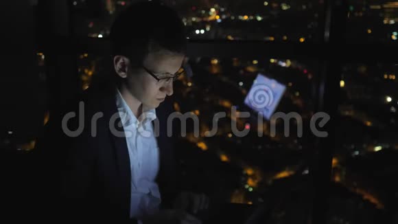 年轻的自由职业者晚上在家窗户附近工作视频的预览图