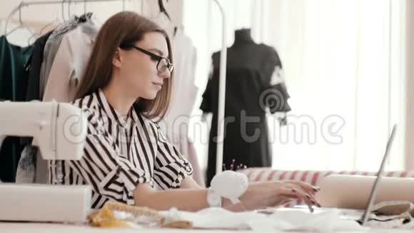 中年白种人的女设计师在笔记本电脑上工作在笔记本上写字视频的预览图