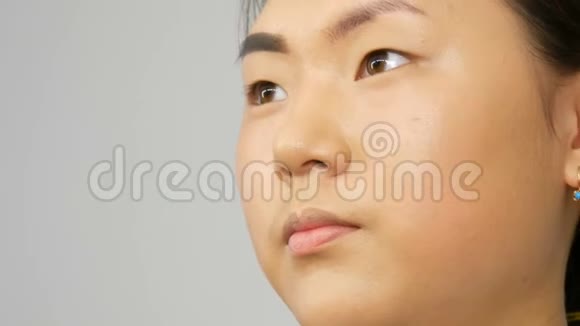 专业化妆师用特殊的画笔在一个亚洲韩国女性模特的脸上画眉毛视频的预览图