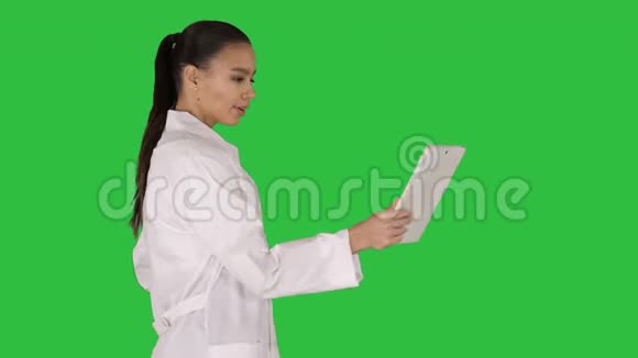 年轻的女医生手里拿着平板电脑在绿色屏幕上打视频电话Chroma键视频的预览图
